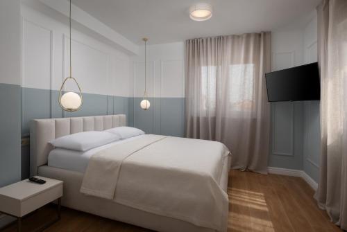 Schlafzimmer mit einem weißen Bett und einem Flachbild-TV in der Unterkunft Villa Bellatrix 1 & 2 - two heated pools & jacuzzi in Vrsi