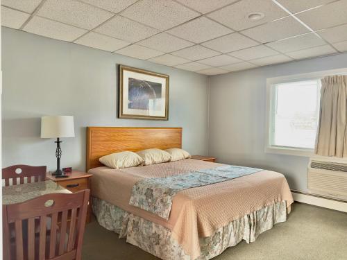 1 dormitorio con cama, mesa y ventana en Colonial Valley Motel, en Farmington