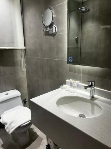 a bathroom with a sink and a toilet and a mirror at الحزم للشقق الفندقية - الرياض - العليا in Riyadh