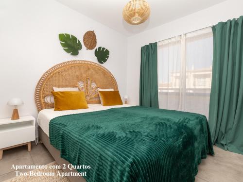 ein Schlafzimmer mit einem Bett mit einer grünen Decke in der Unterkunft Akisol Albufeira Breezy in Olhos de Água