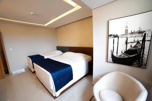Habitación de hotel con 1 cama y 2 sillas en Adria Premium Hotel en Guarapuava