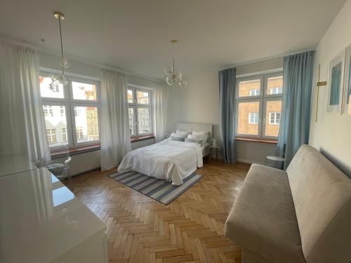 - une chambre avec un lit, un canapé et des fenêtres dans l'établissement Apartament w centrum Gdańska, à Gdańsk