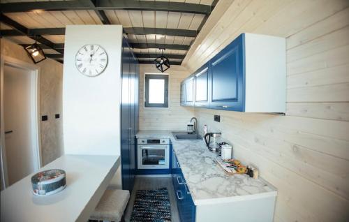 a kitchen with blue cabinets and a clock on the wall at Sirius Lux Apartmani in Žabljak