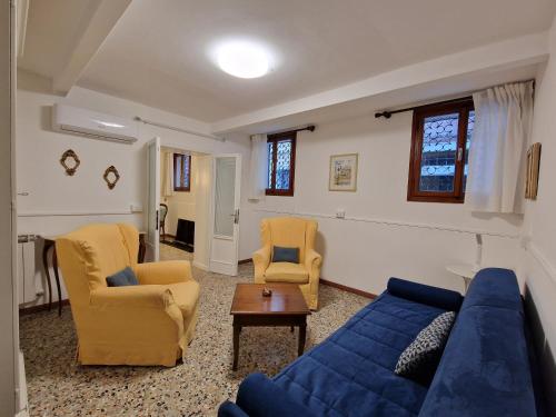 ein Wohnzimmer mit einem blauen Sofa und 2 Stühlen in der Unterkunft Veneziacentopercento Apartments & Rooms in Venedig