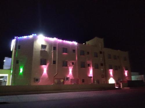 a building with lights on the side of it at night at Hotel Ain Safnan Room&Flats فندق عين صفنان غرف&شقق in Sanāw