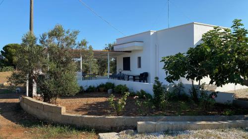 una casa bianca con un giardino di fronte di Mamma Maria Salento - Alle Macchie a Marina di Pescoluse