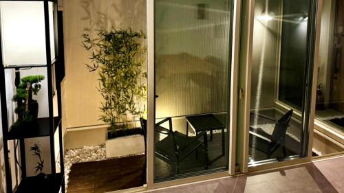 einen Balkon mit einem Stuhl und einer Pflanze in der Unterkunft 加美屋リゾート伊勢神宮 おかげの庭 in Ise