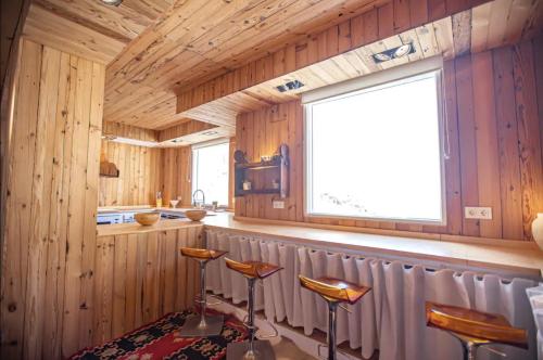 - une cuisine avec des murs en bois, une fenêtre et des tabourets dans l'établissement LUXURY CASA DÚPLEX acceso directo a pistas y garaje, à Sierra Nevada