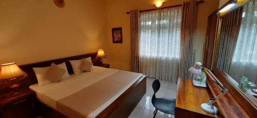 a bedroom with a large white bed and a desk at Kandy Bliss Lounge in Kandy
