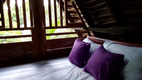 łóżko z fioletowymi poduszkami przed oknem w obiekcie ULPATHA ECO LODGE w mieście Kurunegala