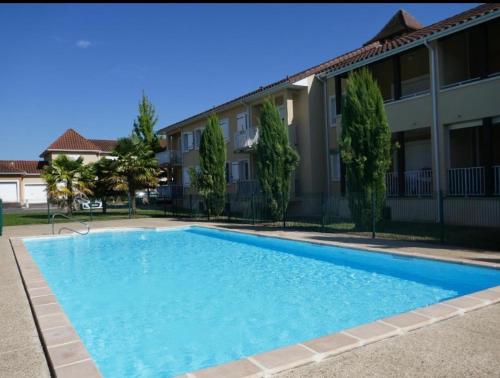 une grande piscine bleue devant un immeuble dans l'établissement Le Lotois les Ondines, à Souillac