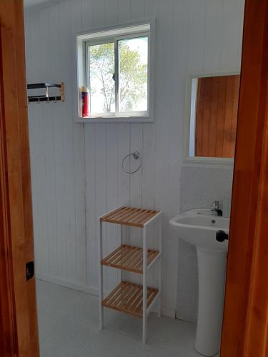 baño con lavabo y aseo y ventana en Cabañas de Campo MARBAJA, en Puerto Montt