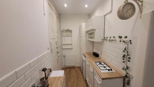 a kitchen with white appliances and a clock on the wall at City Center Gdańska Apartment in Łódź