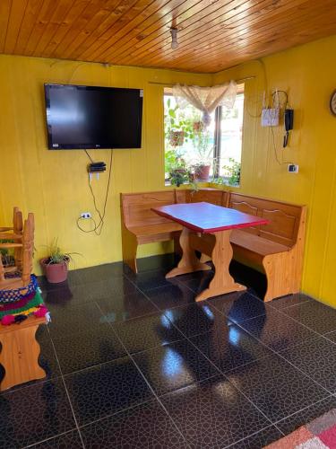 Casa Mía Blue 2 في شيلان: غرفة طعام مع طاولة وتلفزيون على جدار أصفر