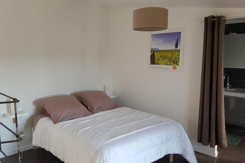 1 dormitorio con 1 cama con sábanas blancas y lavamanos en Les Bories en Taulignan