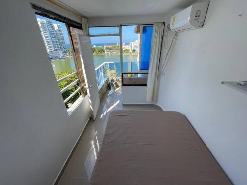 a small room with a bed and two windows at Apartamento laguito vista al mar in Cartagena de Indias