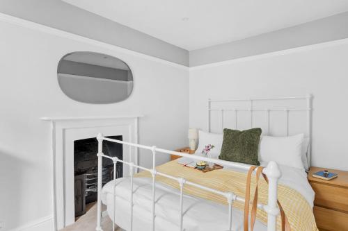 a white bedroom with a bed and a fireplace at Higher Cottage with Parking in Dartmouth