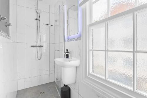 a white bathroom with a sink and a shower at Higher Cottage with Parking in Dartmouth