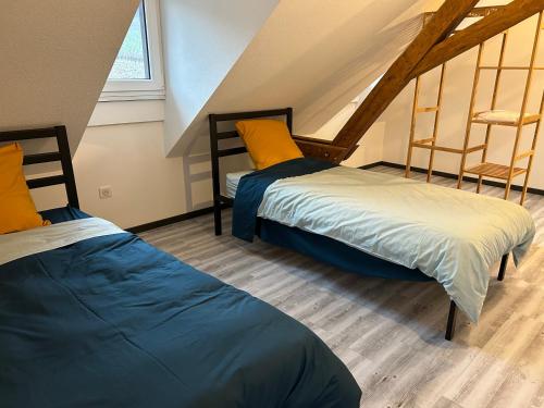 Le Gîte du Taennel في Scherwiller: سريرين في غرفة مع علية