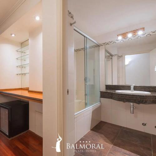 a bathroom with a sink and a glass shower at BALMORAL Triple SUITES in Montevideo
