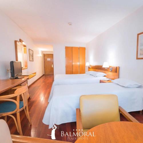 a hotel room with two beds and a desk at BALMORAL PLAZA Hotel in Montevideo