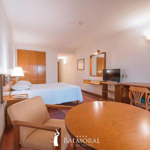 モンテビデオにあるBALMORAL Triple SUITESのベッドとテーブルが備わるホテルルームです。