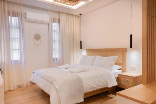 um quarto branco com uma cama grande e lençóis brancos em Boutique 27, luxury apartment. em Ioannina
