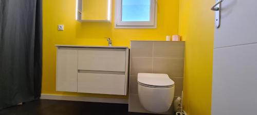 ein Bad mit einem WC und einer gelben Wand in der Unterkunft loft près futuroscope in Montamisé