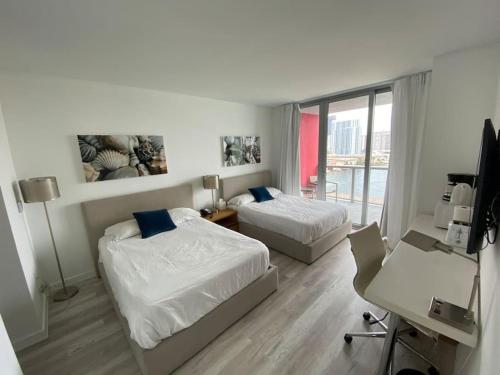 a bedroom with two beds and a desk with a computer at Smart Stay Near the Ocean 2Full Beds Beach Studio in Hallandale Beach