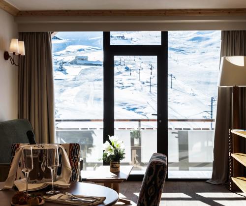 a room with a table and a large window with a mountain view at Alpes Hôtel du Pralong in Courchevel