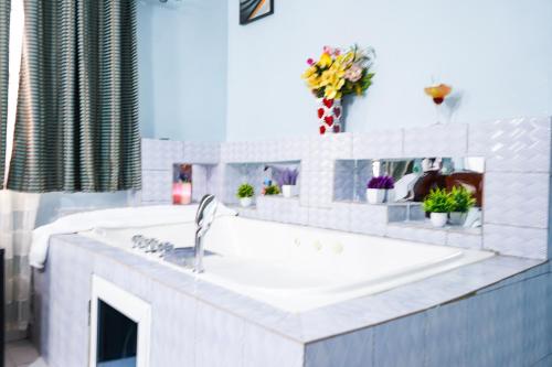 a white kitchen with a sink and flowers on the counter at EKA ELITE HOTEL in Lomé