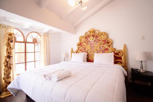 a bedroom with a large white bed with a gold headboard at Hotel Monasterio del Inka in Cusco
