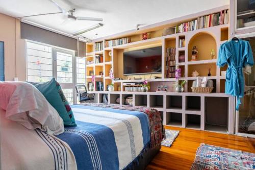 a bedroom with a bed and a tv and bookshelves at Casa Itzae B&B Polanquito Dog Friendly in Mexico City