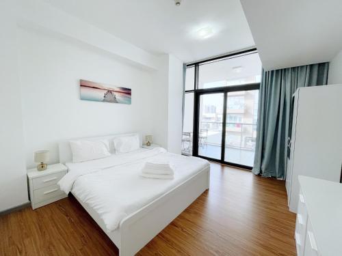 a white bedroom with a white bed and a window at Elite LUX Holiday Homes - One Bedroom Apartment in Silicon Oasis, Dubai in Dubai