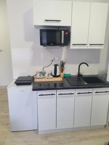a kitchen with white cabinets and a black counter top at Comfort Stay, EV, Parking in Bolesławiec