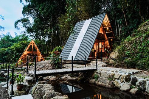 a wooden cabin in a forest next to a river at Senz Glamping - Mindo in Mindo