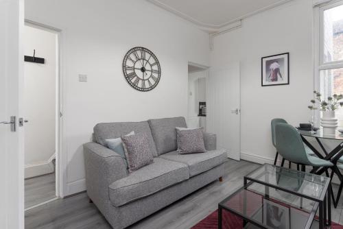 a living room with a couch and a clock on the wall at Host Liverpool - Cozy Home near Univ & Hospital,1mi to Station in Liverpool