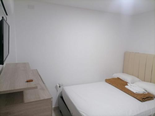 a white bedroom with a bed and a table at Edif HA in Cartagena de Indias