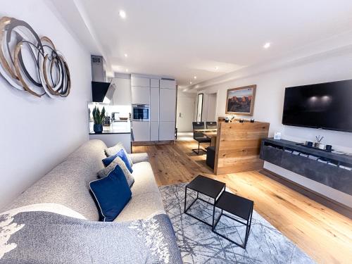uma sala de estar com um sofá, uma televisão e uma cozinha em Alpenluxus' DESIGN LODGE with terrace & car park em Kramsach