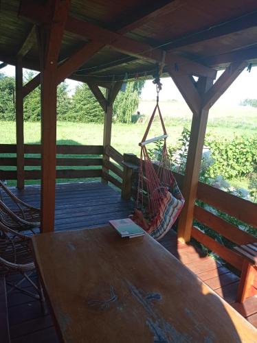 - une terrasse couverte en bois avec une table et un hamac dans l'établissement U Czesiuka, à Jałowo