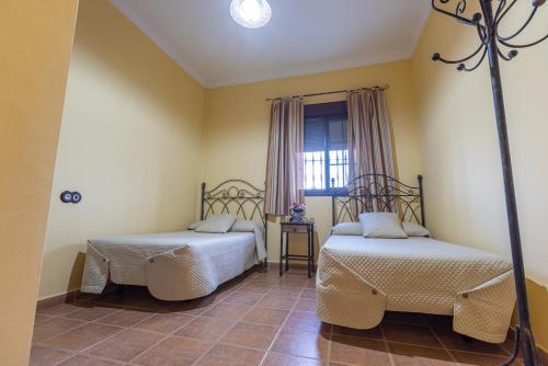 dwa łóżka w pokoju z oknem w obiekcie Casa Rural en el entorno de Doñana w mieście Hinojos