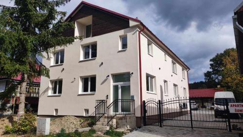 a white building with a black fence in front of it at Apartman Šumiac 4 in Šumiac