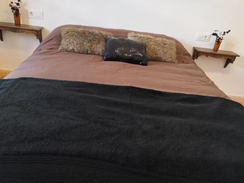 a large bed with a black blanket and two pillows at La casita del vino in Socuéllamos