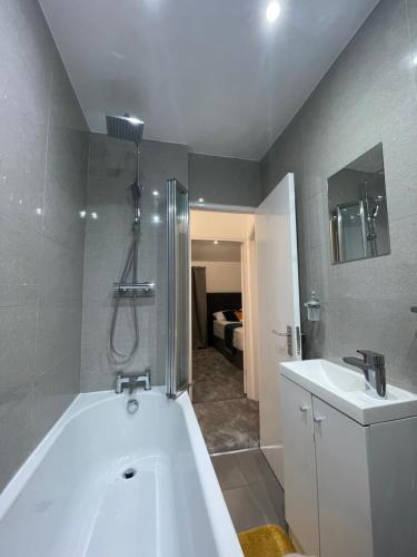 a bathroom with a bath tub and a sink at Tooting Lodge London - Cosy 2 bedroom house with garden in London