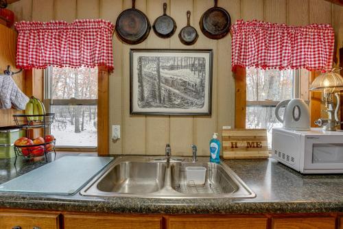 cocina con fregadero y 2 ventanas en Pet-Friendly Irons Cottage about 4 Mi to Sand Lake!, en Irons
