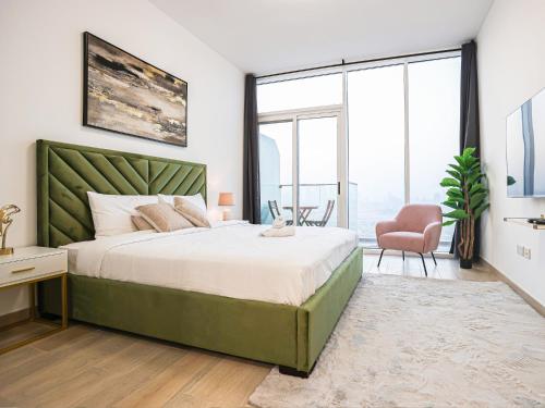 a bedroom with a large bed with a green headboard at Elite LUX Holiday Homes - Luxury Studio in Bloom Towers JVC, Dubai in Dubai