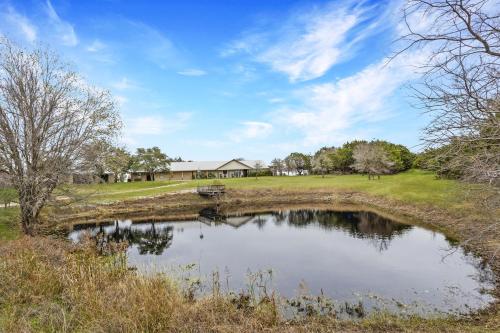 a pond in a field with a house in the background at Rockin' 7 in Glen Rose