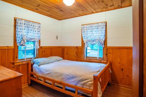a bedroom with a bed and two windows at Smith Family Cottages- Cottage #1 in Indian River