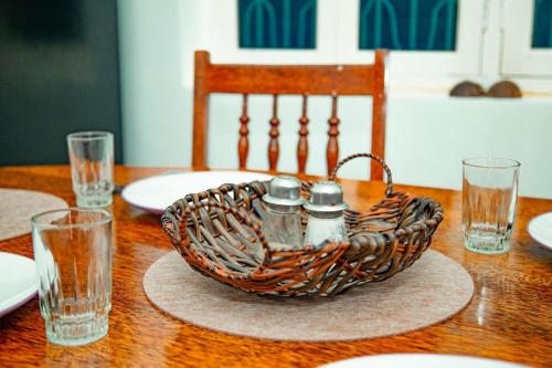 una mesa de madera con una cesta de mimbre con sal y pimienta en Zanzibar Spice Hut Apartment en Stone Town
