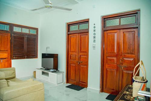a living room with two wooden doors and a tv at Zanzibar Spice Hut Apartment in Stone Town